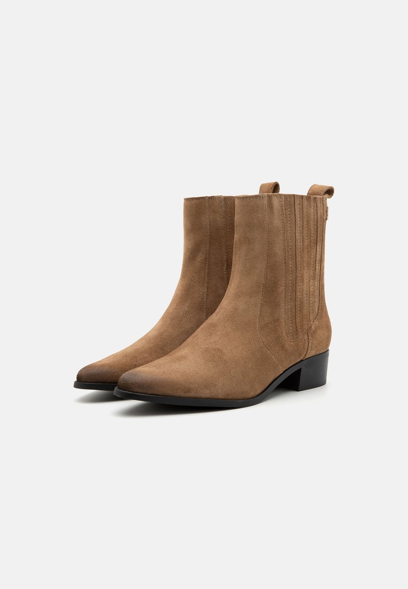Bottes chelsea en suède marron avec un nez pointu, un petit talon carré et des détails de coutures verticales sur les côtés. Texture lisse sur l'ensemble.