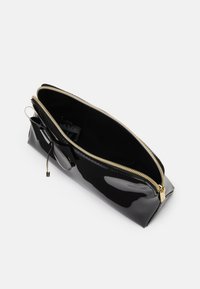 Pochete de cuero negro brillante con un zipper dorado. El interior está forrado en tela negra. Presenta una base estructurada y detalles en el tirador del zipper.