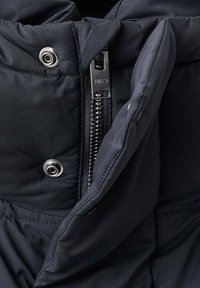 Tamno plavi puffer jakna s vidljivim patentnim zatvaračem i kopčanjem na dugmad, s.features quilted teksturu i sjajnu tkaninu.