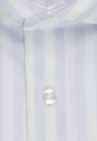 Jasnoniebieska koszula w białe paski z teksturowanej tkaniny, z pojedynczym okrągłym białym guzikiem przy kołnierzyku.