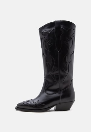 Bota vaquera de cuero negro con costuras decorativas y un tacón medio inclinado sobre un fondo blanco.