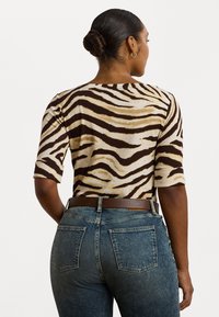 Brun og beige zebra-stripete topp med korte ermer, kombinert med høyt liv blå denim jeans med baklommer og et brunt belte.