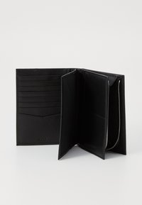 Čierna kožená peňaženka so zipsovým uzatváraním, viacerými priehradkami na karty a textúrovaným povrchom. Vyniká elegantným, minimalistickým dizajnom.