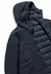 Marine pufferjas met capuchon, voorzien van een gladde buitenstof, gewatteerde isolatie, drukknopen en zijzakken.