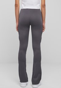 Pelēki riboti uz zemu flared legingi ar teksturētu apdari, ar augsto jostasvietu un pieguļošu piegriezumu, apvienoti ar baltām sporta kedām.