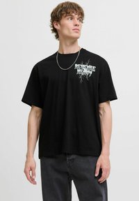 Black cotton t-shirt featuring a graphic print of "Revenge" with a lightning design. Short sleeves, relaxed fit, and round neckline.