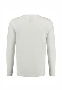 Maglietta a maniche lunghe con scollo rotondo in morbido tessuto beige chiaro. Presenta una leggera texture, una piccola etichetta sul retro e polsini aderenti.