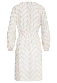 Beige und weißes Kleid mit Zickzackmuster, langen Ärmeln, einem gerafften Rücken und einem Bindegürtel in der Taille. Hergestellt aus einem leichten Stoff.