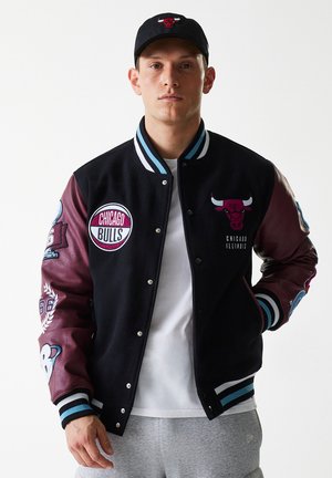 Black varsity jacket with maroon leather sleeves; features Chicago Bulls patches, ribbed cuffs, and contrasting light blue accents.
