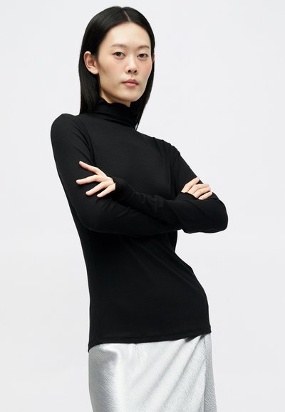 Črn dolg rokav s fitted turtleneck dizajnom, izdelan iz rebraste tkanine, v kombinaciji s srebrno, teksturirano krilo.