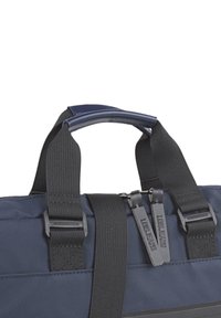 Bolsa de tela azul marino con un asa superior lisa, correas de tejido negro y tiradores de cremallera dobles que presentan la marca "L.O.G.S". Detalles texturizados.