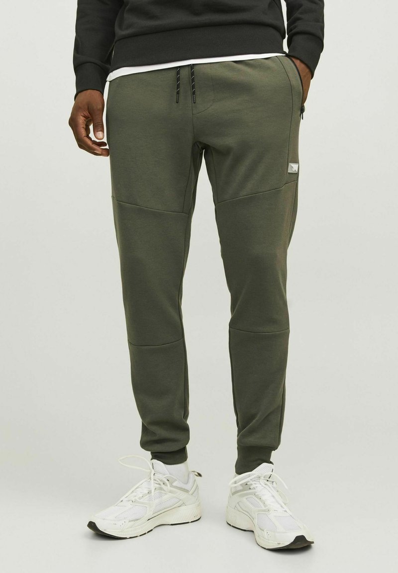 Olijfgroene sweatpants met een tapere pasvorm, gemaakt van een zachte stof. Beschikt over een zijzak, contrasterende panelen en een trekkoord in de taille.