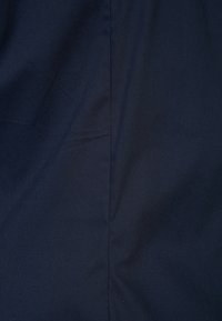 Granatowy materiał o gładkiej fakturze i subtelnym połysku, z fałdami i pionowym szwem na środku.