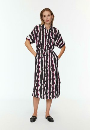 Robe midi rayée avec des lignes ondulées noires, blanches et roses, manches courtes, fermeture à boutons à l'avant et taille ajustable avec cordon.