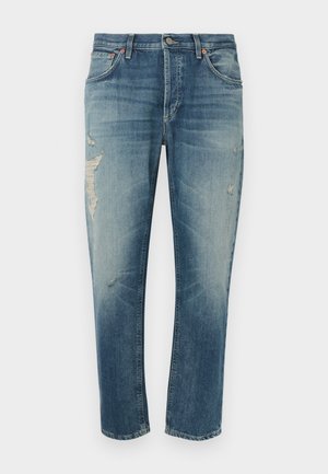 Šviesiai mėlyni džinsai iš džinso audinio su laisvu kirpimu, turintys nudribintas vietas, užsegami mygtuku ir turintys penkias kišenes. Rekomenduojama skalbti skalbyklėje.