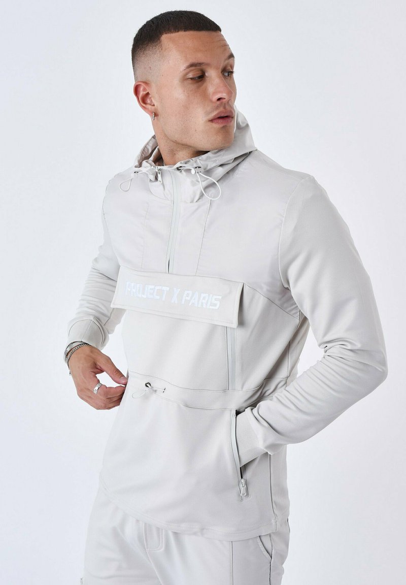 Ljusgrå huvtröja med ficka fram och dragsko. Har "PROJECT X PARIS"-logotyp på en tygpatch, med en strömlinjeformad design.