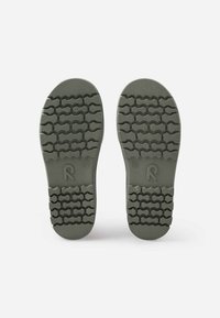 Les semelles de chaussures en caoutchouc vert présentent un motif hexagonal texturé pour une meilleure adhérence, avec un bord supérieur lisse et un logo imprimé près du talon.
