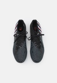 Czarne buty sportowe z teksturowaną cholewką i gumowymi podeszwami. Posiadają czerwone, białe i niebieskie paski po bokach oraz płaskie czarne sznurowadła.