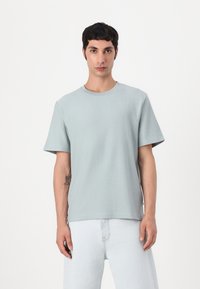Light blue, short-sleeve crew neck t-shirt made of soft, textured fabric, paired with light denim jeans. Simple, relaxed fit.
