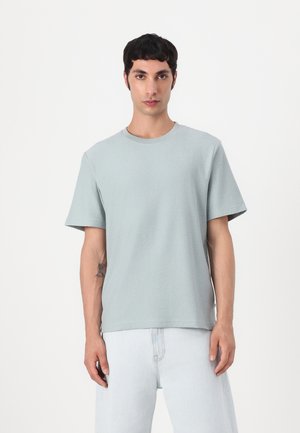 Light blue, short-sleeve crew neck t-shirt made of soft, textured fabric, paired with light denim jeans. Simple, relaxed fit.