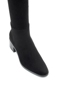 Czarne zamszowe botki do połowy łydki z okrągłym noskiem i niskim, stylowym obcasem na białym tle.
