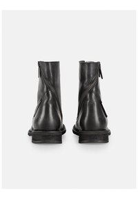 Botas de tobillo de piel negra con un acabado suave, cuentan con cremalleras laterales dobles y un tacón apilado. Los detalles incluyen un logo en el tacón.