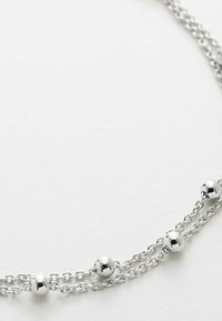 Zilveren ketting met meerdere stranden en gelijkmatig verdeelde ronde kralen. De ketting heeft een delicaat, onderling verbonden ontwerp. Gladde, reflecterende textuur.