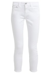 Vaqueros skinnys de mezclilla blanca con una textura suave, cierre de botón y diseño de cinco bolsillos. Las piernas se estrechan hacia el tobillo con puños enrollados.