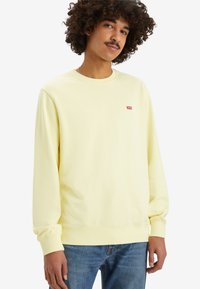 Geel katoenen sweatshirt met lange mouwen, ribgebreide boorden en een ronde hals. Bevat een klein rood Levi's-logo op de borst.