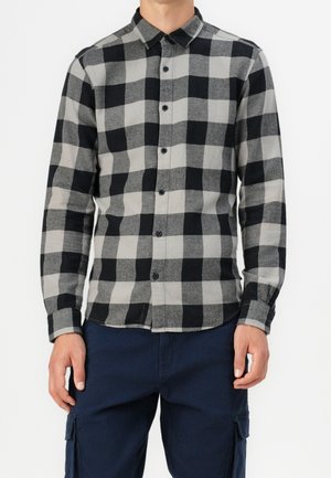 Chemise en flanelle à carreaux noirs et gris avec des manches longues et un col à bouton. Présente un ourlet droit et des boutons noirs à l'avant.