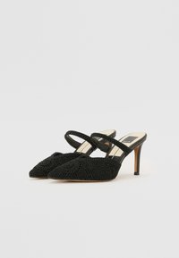 Scarpe nere con tacco realizzate in tessuto testurizzato con un motivo di ricamo floreale. Presentano due cinghie sottili e una punta appuntita.