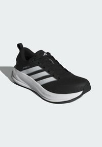 Black athletic shoe with a textured upper, featuring three white stripes, a cushioned sole, and a rounded toe. Detailed “DREAMSTRIKE” branding.