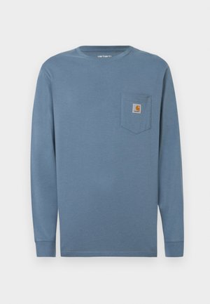 Camisa de algodón azul de manga larga con cuello redondo, bolsillo en el pecho izquierdo y parche con el logotipo de Carhartt. Textura suave, dobladillo recto y mangas ajustadas.