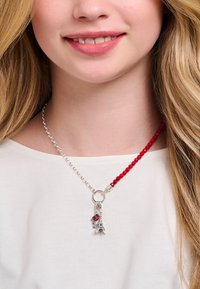 Collier en perles argentées et rouges, orné d'un pendentif en argent en forme de Tour Eiffel avec une accent rose. Matériaux mélangés avec un fermoir décoratif.