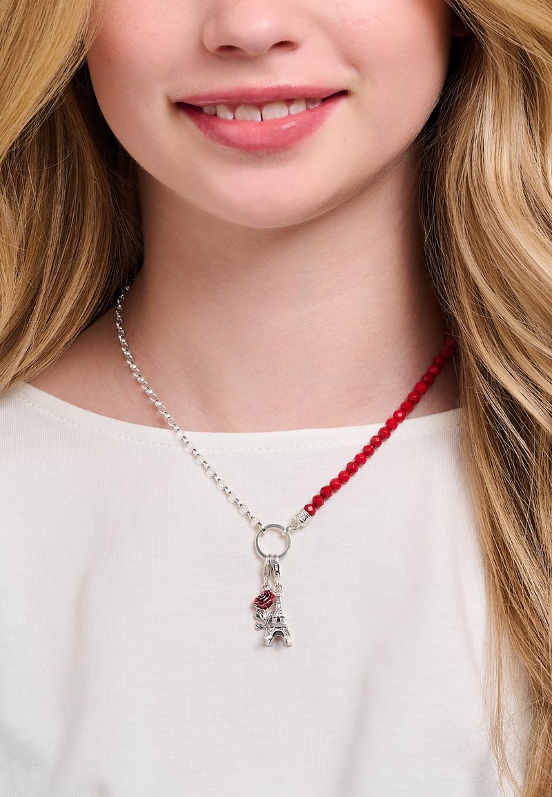 Collier en perles argentées et rouges, orné d'un pendentif en argent en forme de Tour Eiffel avec une accent rose. Matériaux mélangés avec un fermoir décoratif.