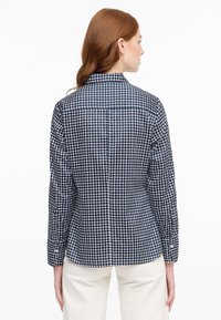 Camicia a maniche lunghe blu navy e bianca a quadri con colletto e polsini abbottonati, caratterizzata da una vestibilità classica e una texture sottile.
