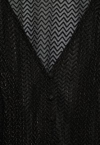 Tissu tricoté noir semi-transparent à motif zigzag, avec deux boutons recouverts de tissu au centre.
