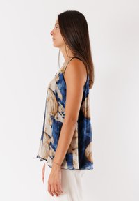 Top senza maniche con un motivo astratto blu e beige, realizzato in tessuto leggero e testurizzato con una silhouette fluida.