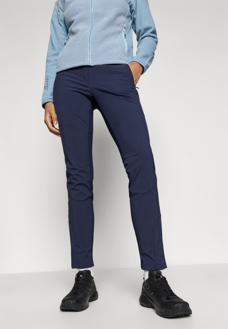 Granatowe spodnie outdoorowe o dopasowanym kroju, z przeszytymi akcentami i kieszeniami, połączone z jasnoniebieską polarową kurtką z zamkiem błyskawicznym oraz czarnymi butami.