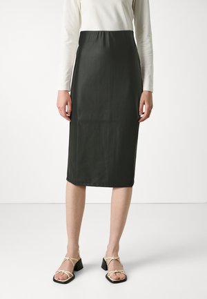 Falda verde oscuro, a la altura de las rodillas, con un acabado suave y mate. Presenta una cintura elástica y se lleva con sandalias de tiras de color claro.