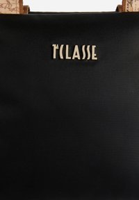 Borsa in nylon nero con logo "T'CLASSE" in tono oro. Il design include manici testurizzati con motivo a scrittura. Forma semplice e strutturata.