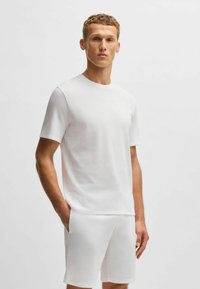 Witte T-shirt met korte mouwen en een gladde textuur, gecombineerd met bijpassende witte shorts. Eenvoudig ontwerp zonder patronen en een ontspannen pasvorm.