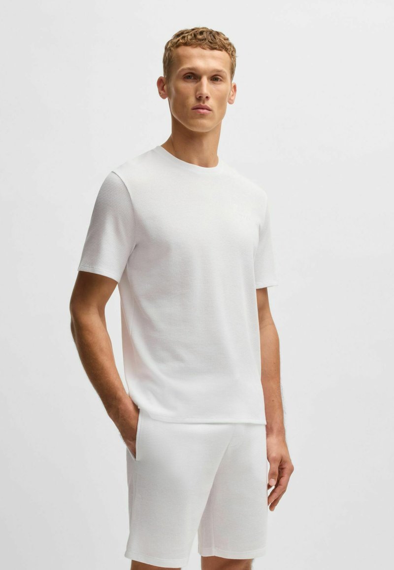 Witte T-shirt met korte mouwen en een gladde textuur, gecombineerd met bijpassende witte shorts. Eenvoudig ontwerp zonder patronen en een ontspannen pasvorm.