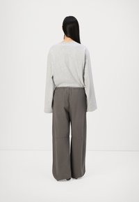 Un haut gris à manches longues avec une coupe décontractée, assorti à un pantalon large gris foncé avec une taille élastique et des poches latérales.