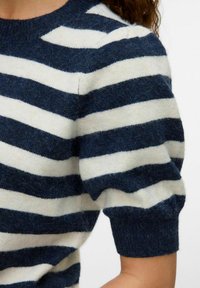 Maglione a righe blu navy e crema con scollo arrotondato, maniche corte a palloncino e una consistenza morbida e pelosa. Dettagli a coste nei polsini e nell'orlo.