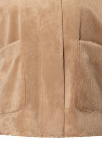 Beige Kunstfelljacke mit einer weichen, strukturierten Oberfläche, zwei vorderen Taschen und einer nahtlosen Mittelnaht für ein glattes Finish.