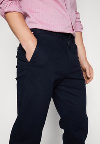 Chinos in cotone blu navy con vestibilità regolare, dotati di tasche laterali, chiusura con zip e una finitura liscia al tatto.