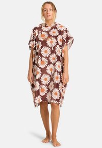 Poncho marrón de gran tamaño con estampado de margaritas en crema y naranja. Material suave, mangas cortas y capucha. Presenta detalles de costura en el cuello.
