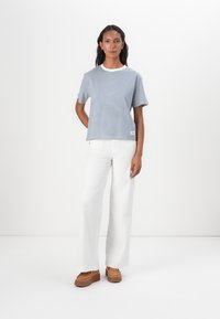 Tricou striped albastru și alb cu guler rotund, asortat cu pantaloni largi albi și pantofi cu platformă maro. Material neted, casual.