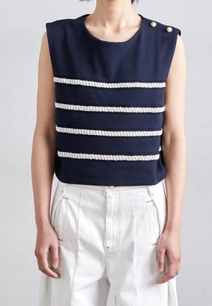 Granatowy top bez rękawów z poziomymi białymi, teksturowanymi paskami, z dwoma dekoracyjnymi guzikami na ramieniu oraz okrągłym dekoltem.